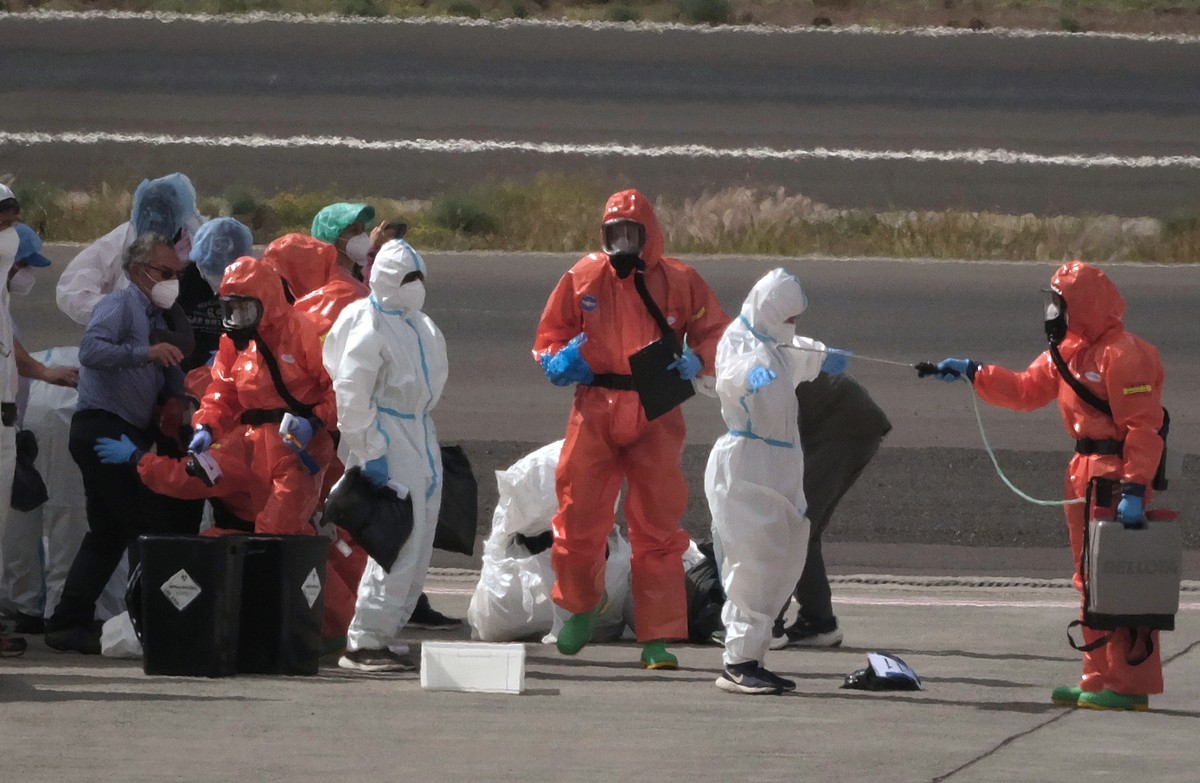 Passengers are sprayed with disinfectant by Spanish government officials before boarding a plane after disembarking from the hantavirus-stricken cruise ship MV Hondius at Tenerife airport in the Canar ...