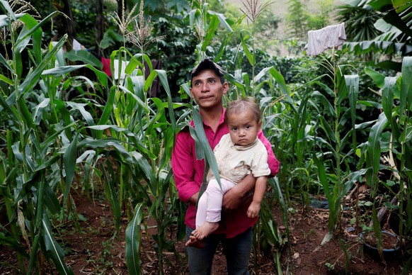 Photo taken on October 26, 2019 that shows the 4-year-old Carla girl being carried by her adoptive father Roque in front of the cornfield of her property, they live in the village of El Ceibal in the  ...