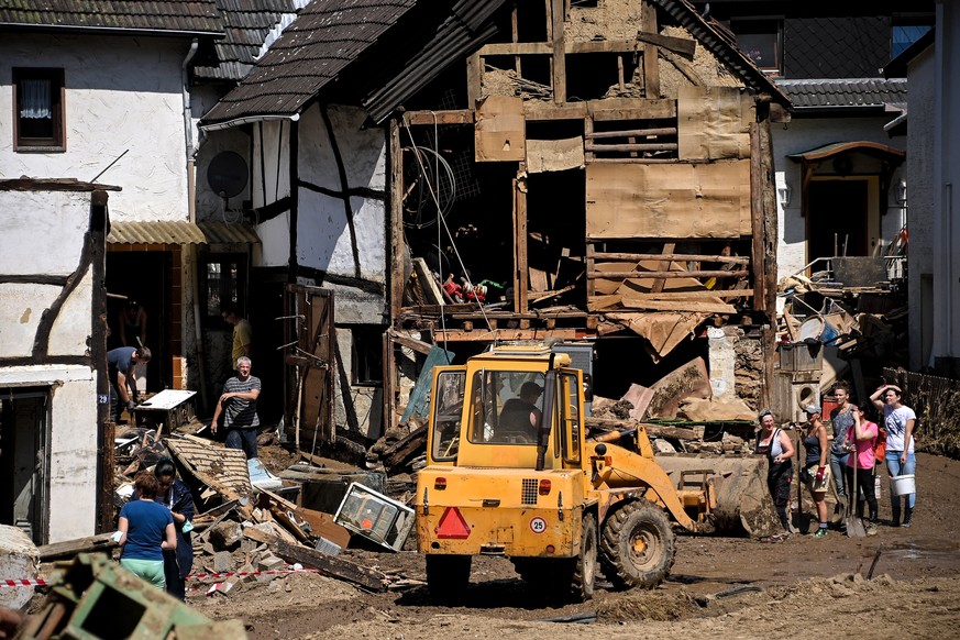 epa09351796 Residents of the Rhineland-Palatinate village of Schuld clear debris out of the way after the flooding of the Ahr River, in Schuld, Germany, 18 July 2021. Large parts of Western Germany we ...