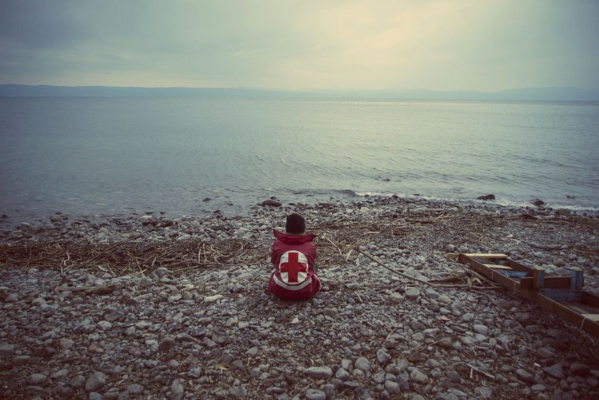 Ein Mann des griechischen Roten Kreuzes wartet am Strand von Lesbos auf ankommende Flüchtlinge.<br data-editable="remove">