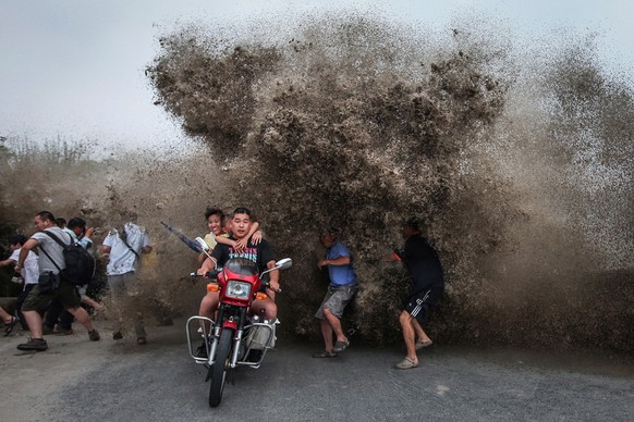 Jahr für Jahr sammeln sich Schaulustige und Gefahrensucher am Qiantang-Fluss in China, der für seine hohe Gezeitenwelle «Silberner Drache» bekannt ist.