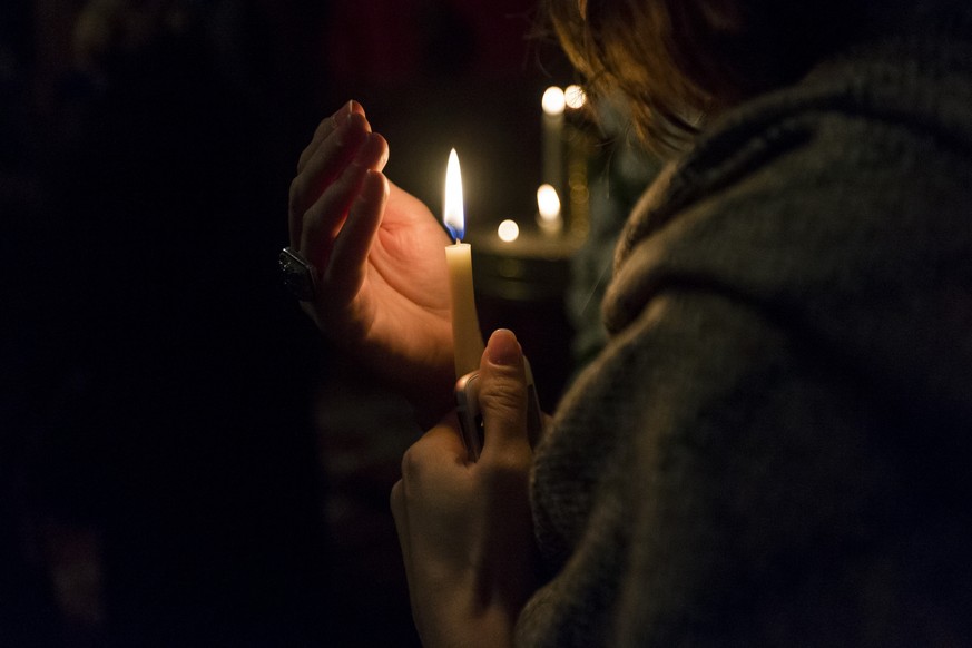 A woman holds a candle during the deathwatch at the coffin of former King of Romania Michael I, on Monday, December 11, 2017, at the Greek Orthodox Church of Lausanne, in Lausanne, Switzerland. Michae ...