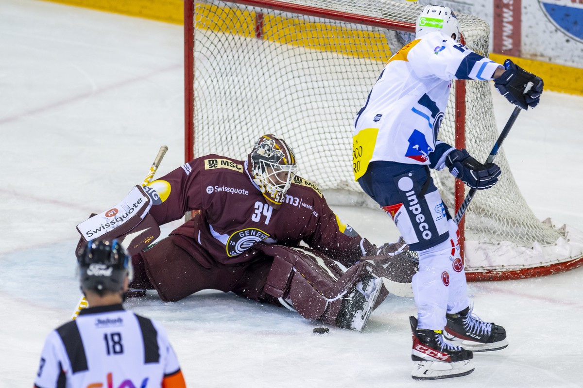 Le gardien genevois Gauthier Descloux, gauche, a la lutte pour le puck avec l'attaquant tessinois Laurent Dauphin, droite, lors du match du championnat suisse de hockey sur glace de National Leag ...