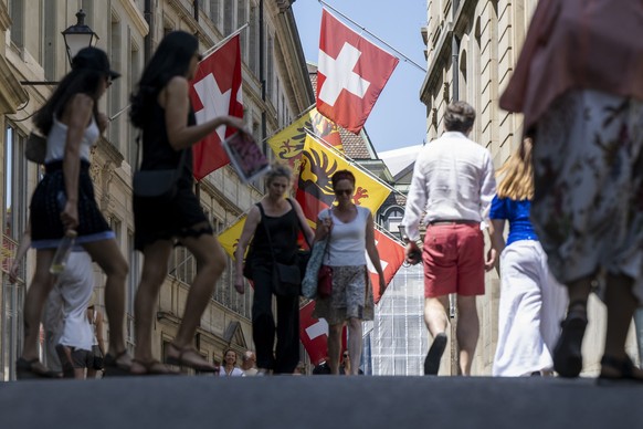 Des personnes se baladent dans la rue de l'hotel de ville en vieille ville de Geneve, pavoiser de drapeaux aux couleurs de Geneve et de la Suisse et de l'union europeenne, ce dimanche 22 jui ...