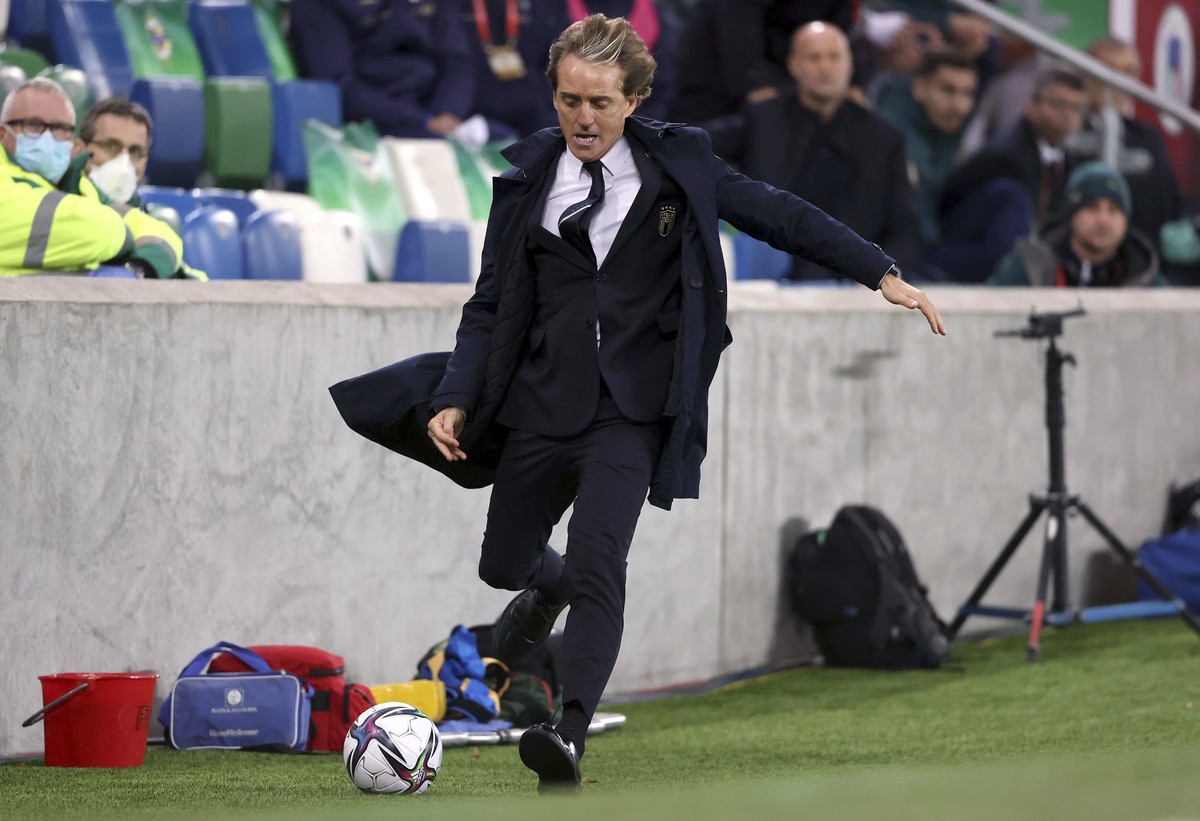Italy manager Roberto Mancini races to collect the ball as it goes out of play during the World Cup 2022 group C qualifying soccer match between Northern Ireland and Italy at Windsor Park stadium in B ...