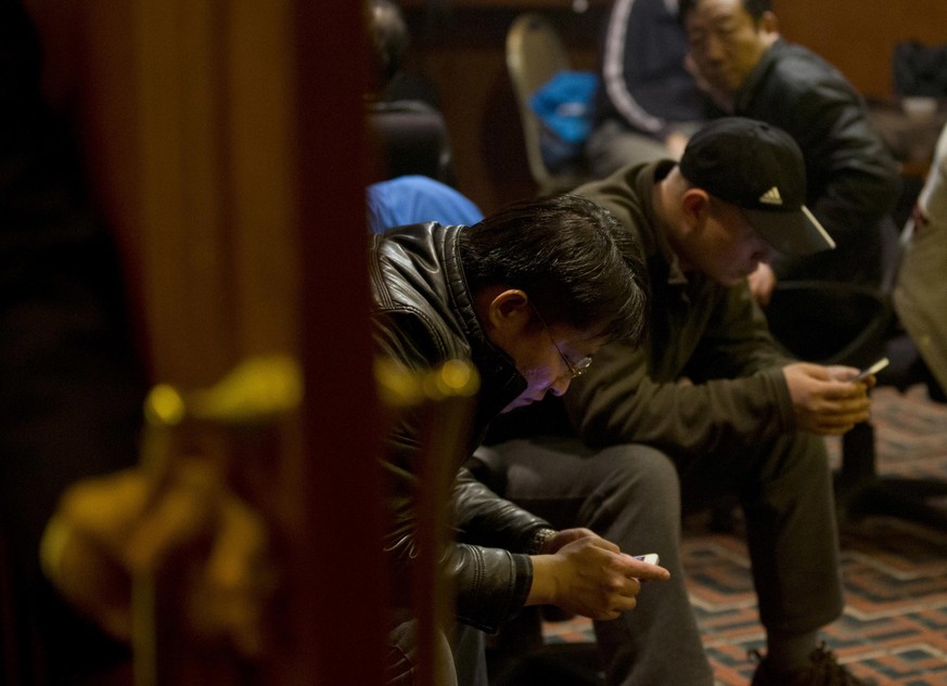 Chinese relatives of passengers aboard a missing Malaysia Airlines plane browse their smartphone for the latest news inside a hotel room set aside for relatives or friends of passengers aboard the mis ...