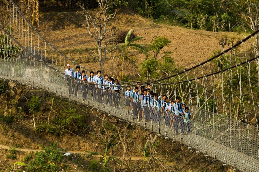 Line of School Children cross suspension bridge over the Trishuli river at Malekhu Village of Dhading Disrict, some 85 Kilometer west from capital Kathmandu, Nepal. Hundreds of school Children of Kump ...