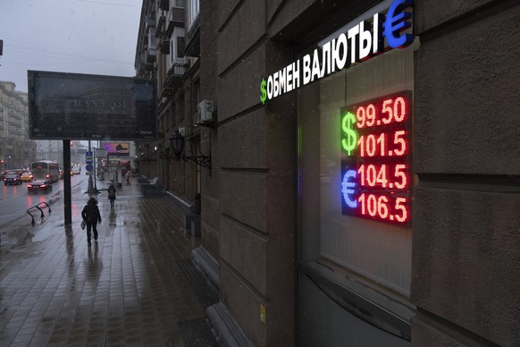 Pedestrians walk in a street near an exchange office sign showing the currency exchange rates of the Russian ruble, U.S. dollar, and euro in Moscow, Russia, Wednesday, Nov. 20, 2024. (AP Photo/Alexand ...