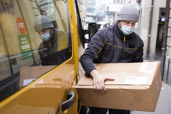 Ein Paketbote der Post stapelt waehrend der Auslieferung die Pakete auf einen Wagen, am Donnerstag, 11. Februar 2021, in Bern. (KEYSTONE/Peter Klaunzer)