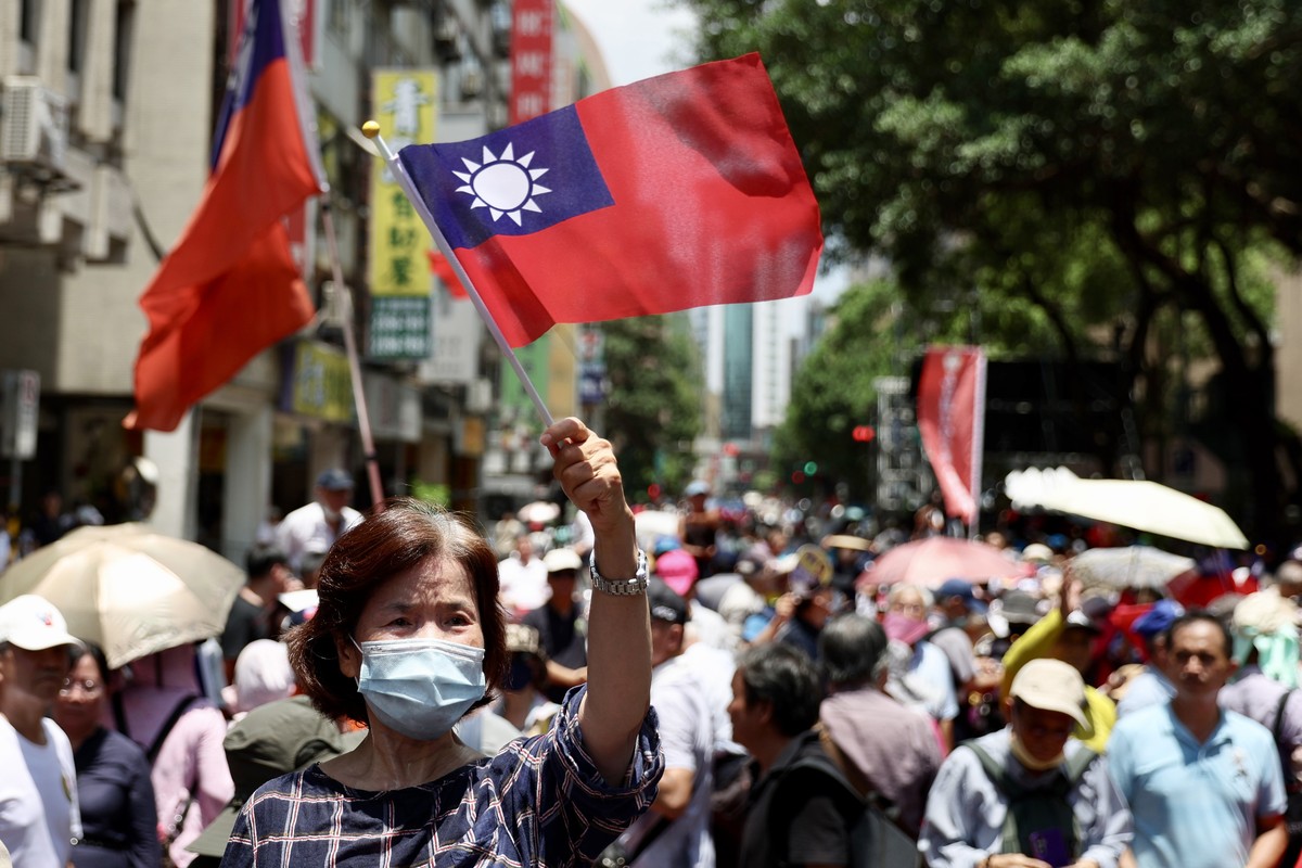 epa11427206 A supporter of the opposition party Kuomintang waves Taiwan's national flag after the party won the majority vote on the government oversight bill, outside the legislative yuan buildi ...