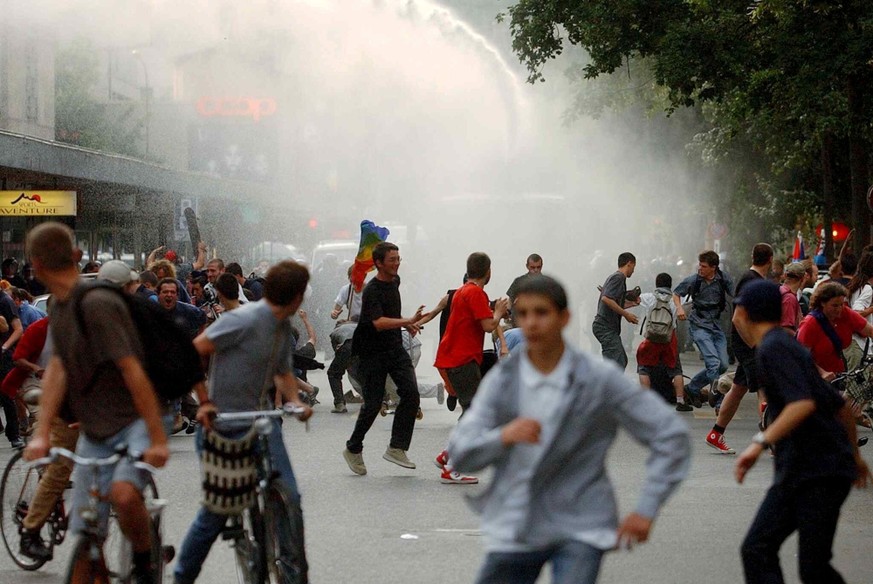 Protesters run away from water cannons and tear gas during clashes with riot police in Geneva, Switzerland, Tuesday, June 3, 2003. After the end of the G8 summit in Evian clashes between activists and ...