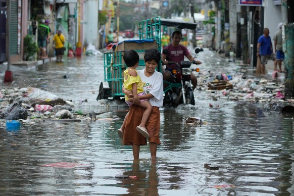 A woman and child crosses a flooded street due to Typhoon Fung-wong and high tide on Monday, Nov. 10, 2025, in Navotas, Philippines. (AP Photo/Aaron Favila)
Philippines Extreme Weather Asia Typhoon