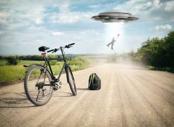 Landscape with bike on the road and UFO. Fiction scene with alien spaceship. Photo with 3d rendering element and vintage film camera effects