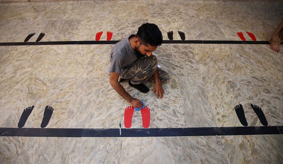 epaselect epa08379998 A worker marks the ground for congregants to keep distance during prayers at a Mosque ahead of the Muslims holy fasting month of Ramadan, during lockdown of the Sindh province du ...