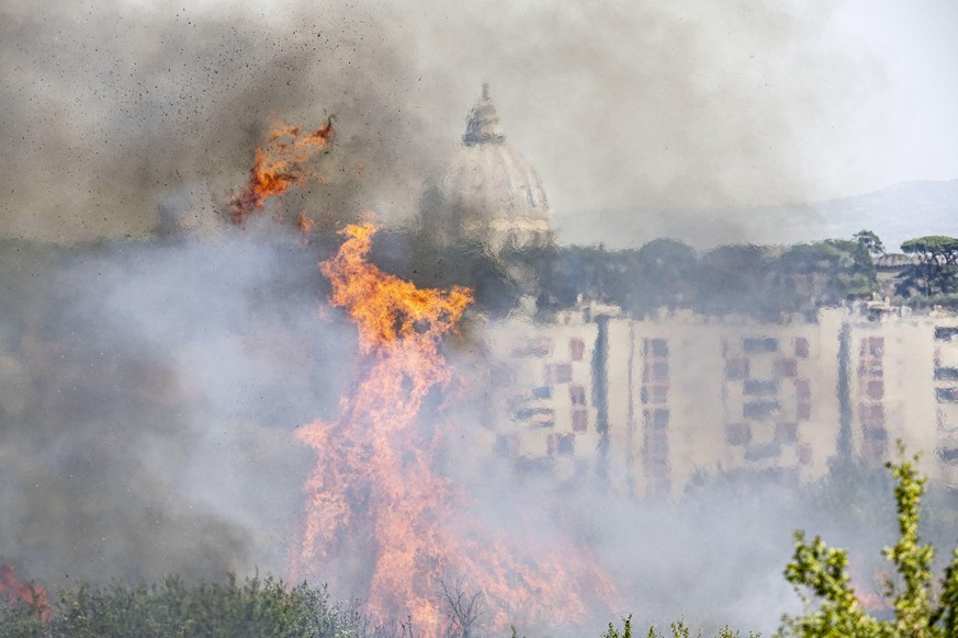 epa10051631 The dome of St. Peter&#039;s Basilica is seen through smoke rising from a fire that erupted in a park area in the north of Rome, Italy, 04 July 2022. The fire, fueled by hot winds, affecte ...