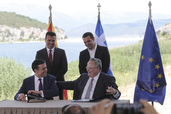 Greek Prime Minister Alexis Tsipras, background right, and his Macedonian counterpart Zoran Zaev, background left, look on as Greek Foreign Minister Nikos Kotzias, right, and his Macedonian counterpar ...