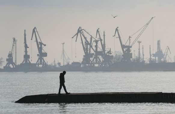 FILE - A man walks with harbor cranes in the background, at the trade port in Mariupol, Ukraine, Wednesday, Feb. 23, 2022. Russia began evacuating its embassy in Kyiv, and Ukraine urged its citizens to leave Russia. Unbroken by a Russian blockade and relentless bombardment, the key port of Mariupol is still holding out, a symbol of staunch Ukrainian resistance that has thwarted the Kremlin's invasion plans. (AP Photo/Sergei Grits, File)