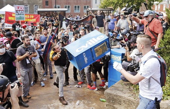 FILE - In this Aug. 12, 2017 file photo, white nationalist demonstrators, right, clash with a counter demonstrator as he throws a newspaper box at the entrance to Lee Park in Charlottesville, Va. The  ...