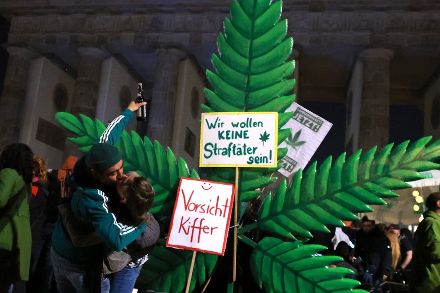 epa11254019 Participants kiss in front of a giant hemp leaf at the Brandenburg Gate on the occasion of a so called &#039;Smoke-In&#039; event in Berlin, Germany, 01 April 2024. Activists and supporter ...