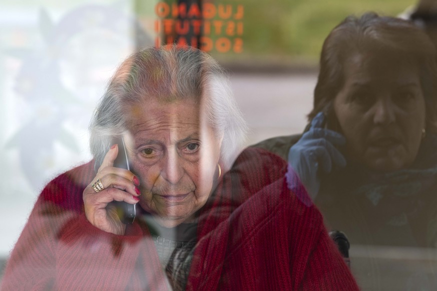 Monica telefoniert durch eine Scheibe mit ihrer 88-jaehrigen Mutter Giuseppina, am Mittwoch, 1. April 2020, im Altersheim Serena in Lugano. Aufgrund des Coronavirus wird ein direkter Kontakt vermieden ...