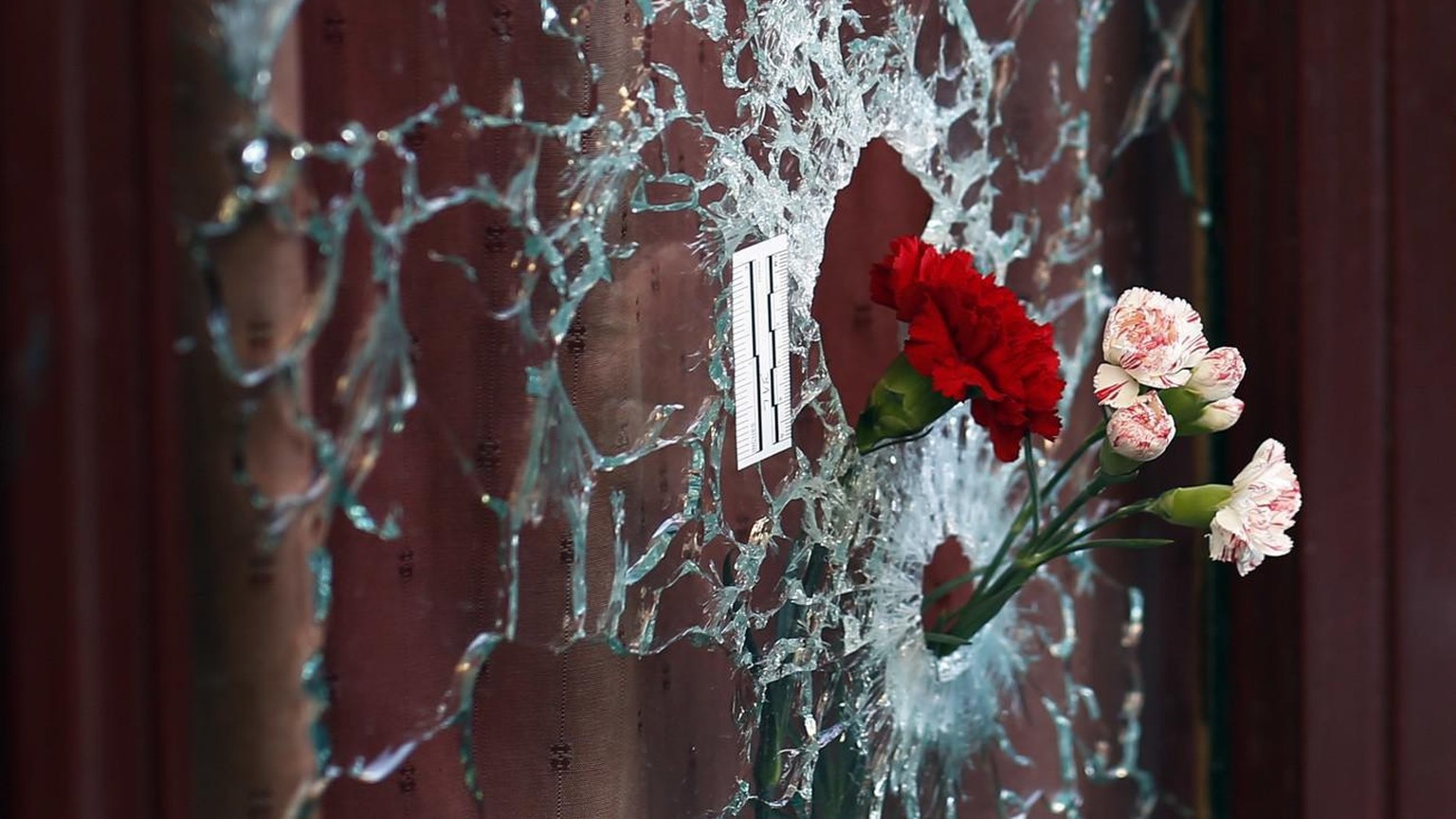 Flowers are set in a window shattered by a bullet at the Carillon cafe in Paris, France, Sunday Nov. 15, 2015, two days after over 120 people were killed in a series of shooting and explosions. French ...