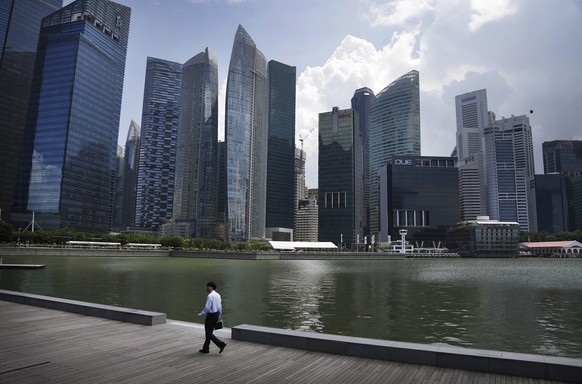 An office worker walks along the Singapore River front during the lunch hour Monday, May 5, 2014 in the central business district of Singapore. (AP Photo/Wong Maye-E)
