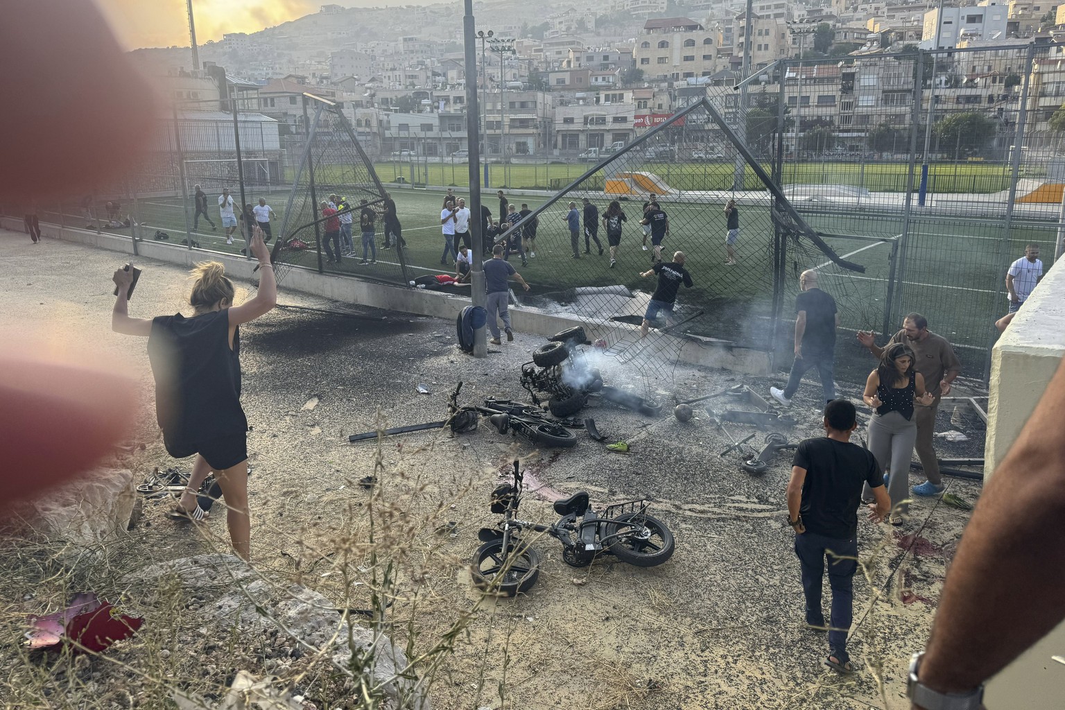 Residents rush to help injured children moments after a rocket attack hit a soccer field in the Druze town of Majdal Shams in the Israeli-controlled Golan Heights, Saturday, July 27, 2024. (AP Photo/H ...