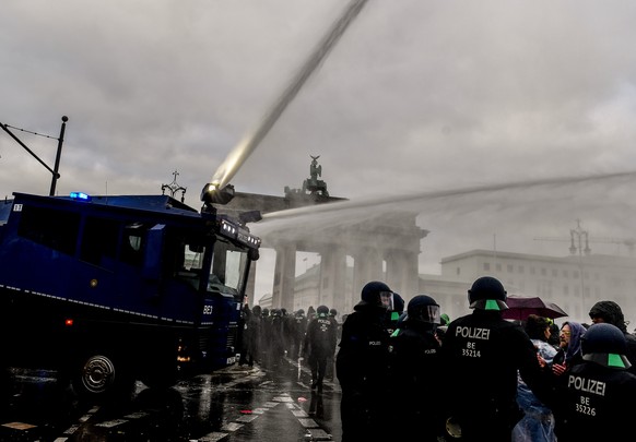 epa08827960 Riot police uses a water cannon to break up a demonstration against German coronavirus restrictions, near the Brandenburg Gate in Berlin, Germany, 18 November 2020. While German interior m ...