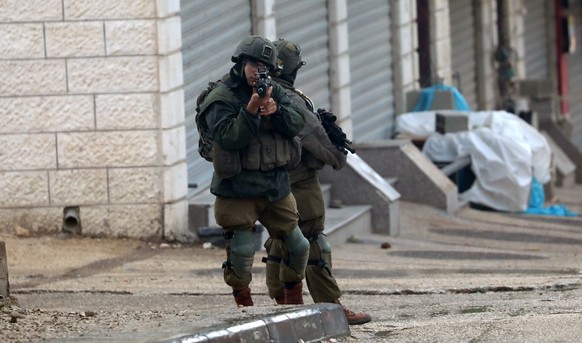 epa10532437 Israeli soldiers stop a Palestinian man in the area following a shooting attack in the West Bank town of Hawara, near the city of Nablus, 19 March 2023. The Israeli Army said on 19 March t ...