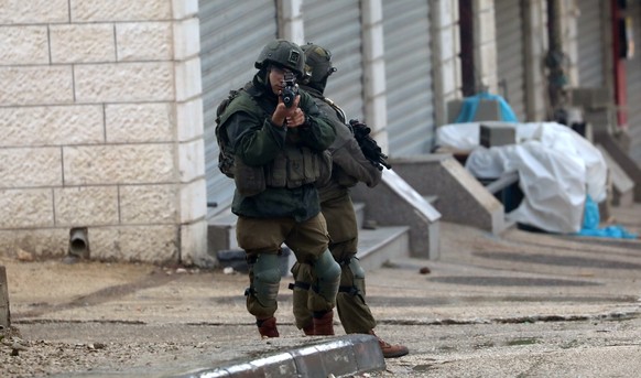 epa10532437 Israeli soldiers restrain a Palestinian man in the area after a shooting in the West Bank town of Hawara, near the city of Nablus, March 19, 2023. The Israeli army said on March 19…