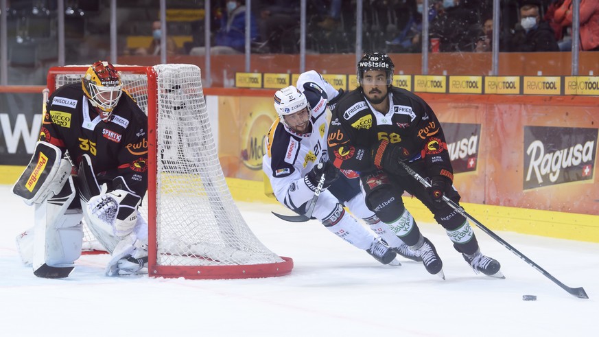 Berns Eric Blum, rechts, und Ambris Daniele Grassi, Mitte, kaempfen um den Puck an der Seite Berns Torhueter Tomi Karhunen, links, beim Eishockey Meisterschaftsspiel der National League zwischen dem S ...