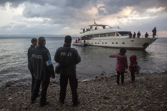Frontex security personnel watch refugees and migrants disembarking from a yacht on the Greek island of Lesbos, after crossing a part of the Aegean sea from Turkey&#039;s coast, early in the morning S ...