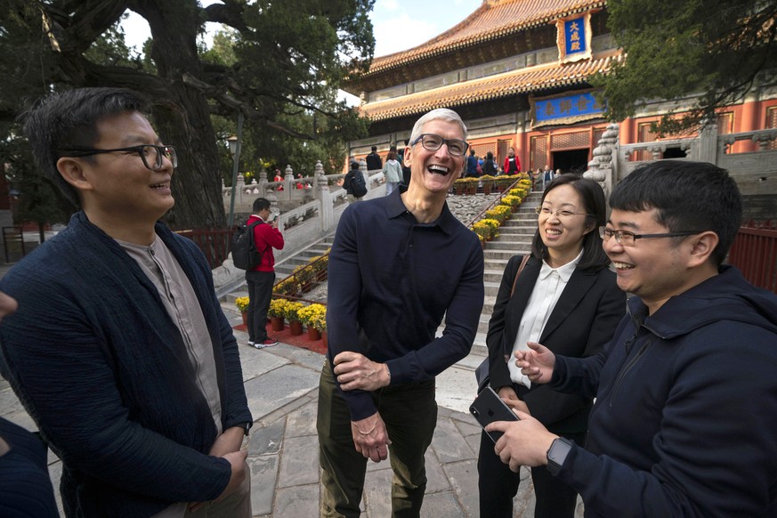In this Oct. 10, 2018 photo released by China&#039;s Xinhua News Agency, Apple CEO Tim Cook, center, talks with Qu Zhangcai, left, and Liu Zhipeng, right, founders of the Xichuangzhu software app, dur ...