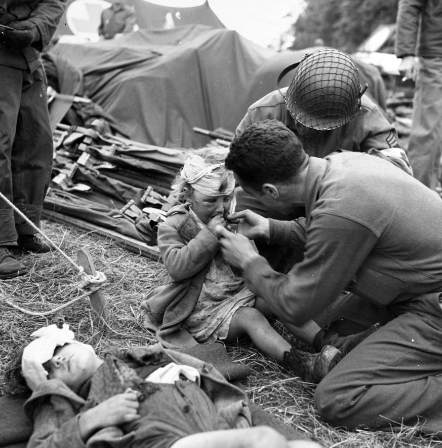 A U.S. Army medical corpsman gives candy to a young French girl, injured during the Allied invasion of German-occupied France. Photograph released June 17, 1944. PUBLICATIONxINxGERxSUIxAUTxHUNxONLY WA ...