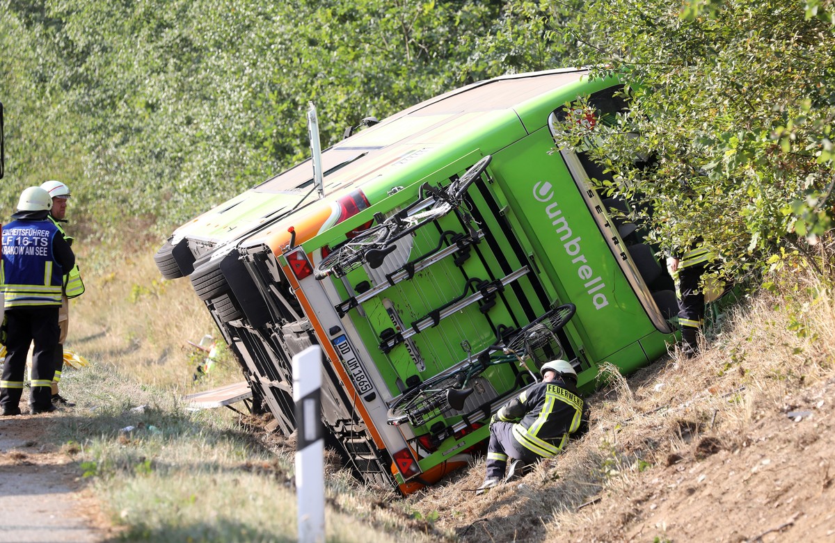 17.08.2018, Mecklenburg-Vorpommern, Linstow: Feuerwehrmaenner stehen an einem Flixbus, der im Strassengraben der Autobahn A19 Rostock-Berlin liegt. Der Fernbus ist aus ungeklaerter Ursache nach rechts ...