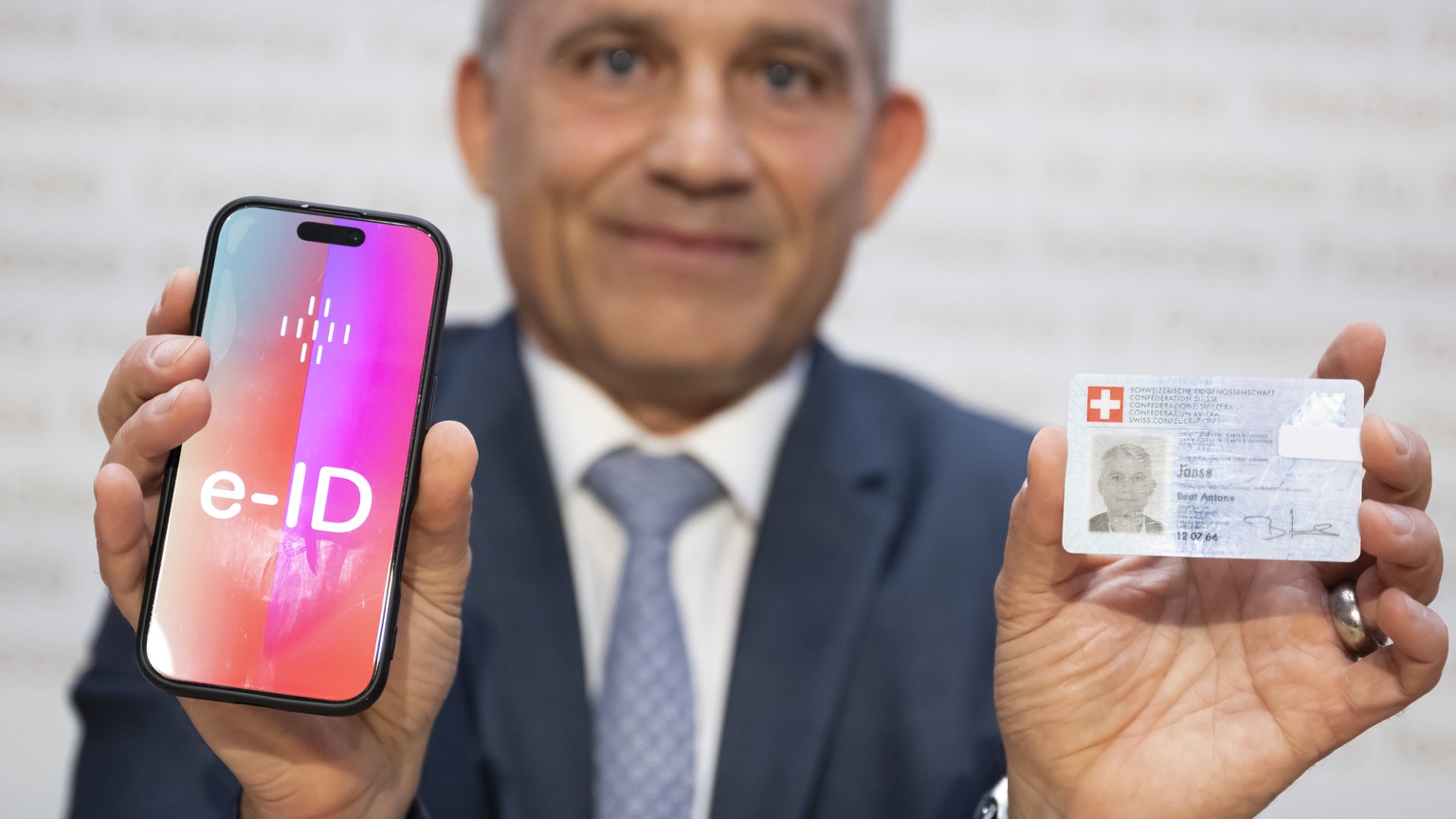 Bundesrat Beat Jans, posiert und haelt ein Handy mit der Aufschrift e-ID sowie seine Identitaetskarte in den Haenden, nach einer Medienkonferenz im Hinblick auf die Volksabstimmung vom 28. September 2 ...