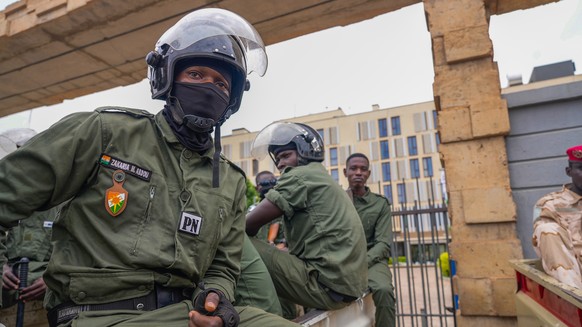 Nigerien police officers sit outside the customs offices in Niamey, Niger, Monday, Aug. 21, 2023. Around 300 trucks of food and other materials crossed into Niger from Burkina Faso with many arriving  ...