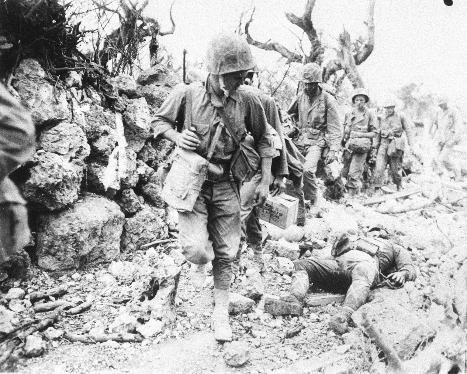 In this April, 1945, photo, a U.S. soldier walks past the body of a Japanese soldier in Okinawa, southern Japan. More than 200,000 people, about half of them civilians and about 12,500 American soldie ...