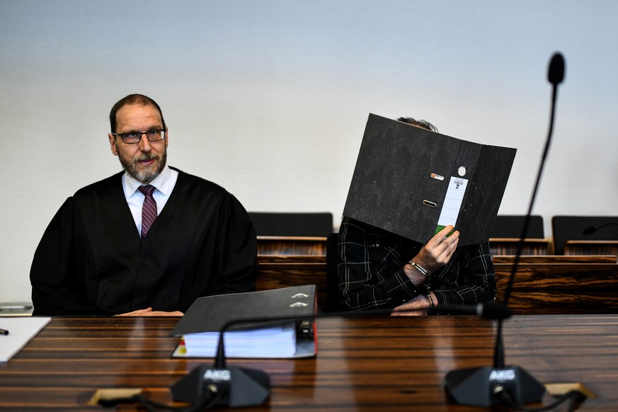 Der wegen Kindesmissbrauchs angeklagte Juergen W. aus der Schweiz sitzt mit einem Ordner vor dem Gesicht in einem Saal des Landgerichts neben seinem Anwalt Robert Phleps, fotografiert am 6. Juni 2018. ...