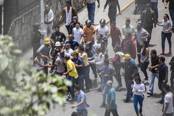 epa06100395 A protester is detained by workers near the offices of state-owned Venezolana de Television (VTV) television station in Caracas, Venezuela, 20 July 2017. Members of the National Bolivarian ...