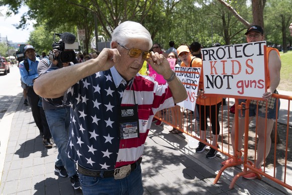 Ein Mitglied der NRA hält sich in Houston, Texas, die Ohren zu, während er an den wütenden Demonstranten vorbeitläuft.