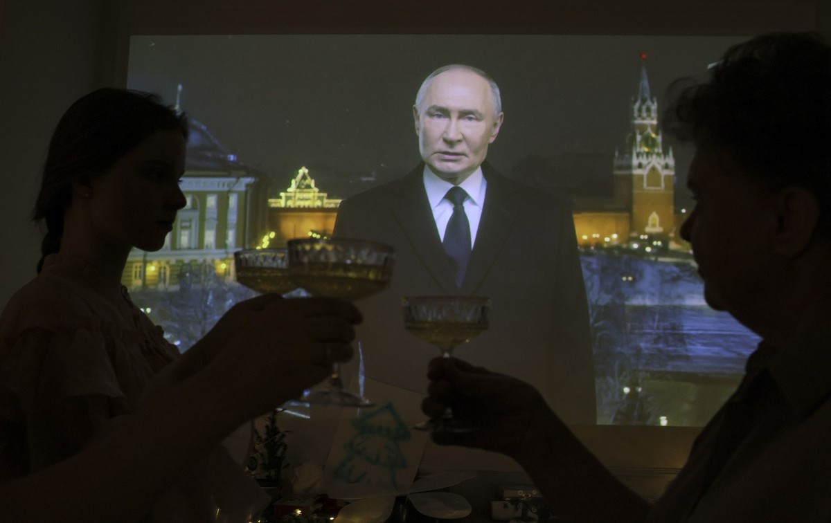 Des personnes trinquent en écoutant le discours annuel du Nouvel An du président russe Vladimir Poutine (à l'écran) chez elles à Moscou, Russie, le 1er janvier 2025.