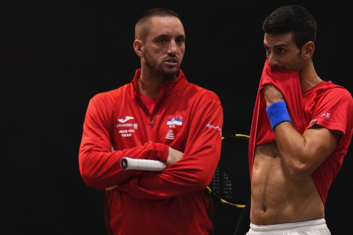 Serbia's Novak Djokovic, right, reacts as he listens to captain of Team Serbia Viktor Troicki during a training session of the Davis Cup in Malaga, Spain, Tuesday, Nov. 21, 2023. (AP Photo/Manu F ...