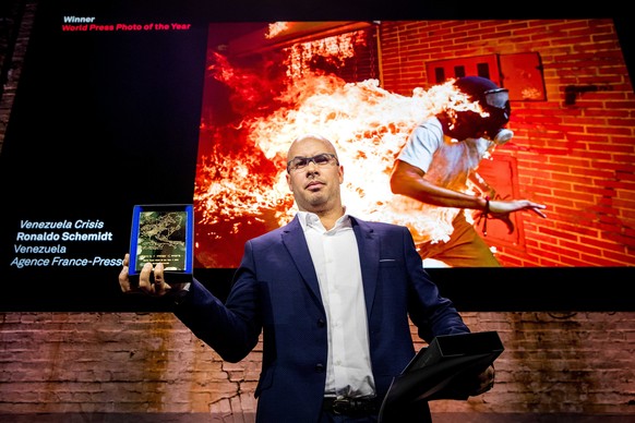 epaselect epa06665182 Winner of the World Press Photo 2018 Awards photographer Ronaldo Schemidt poses in front of his winning picture during the World Press Photo Award ceremony in Amsterdam, The Neth ...