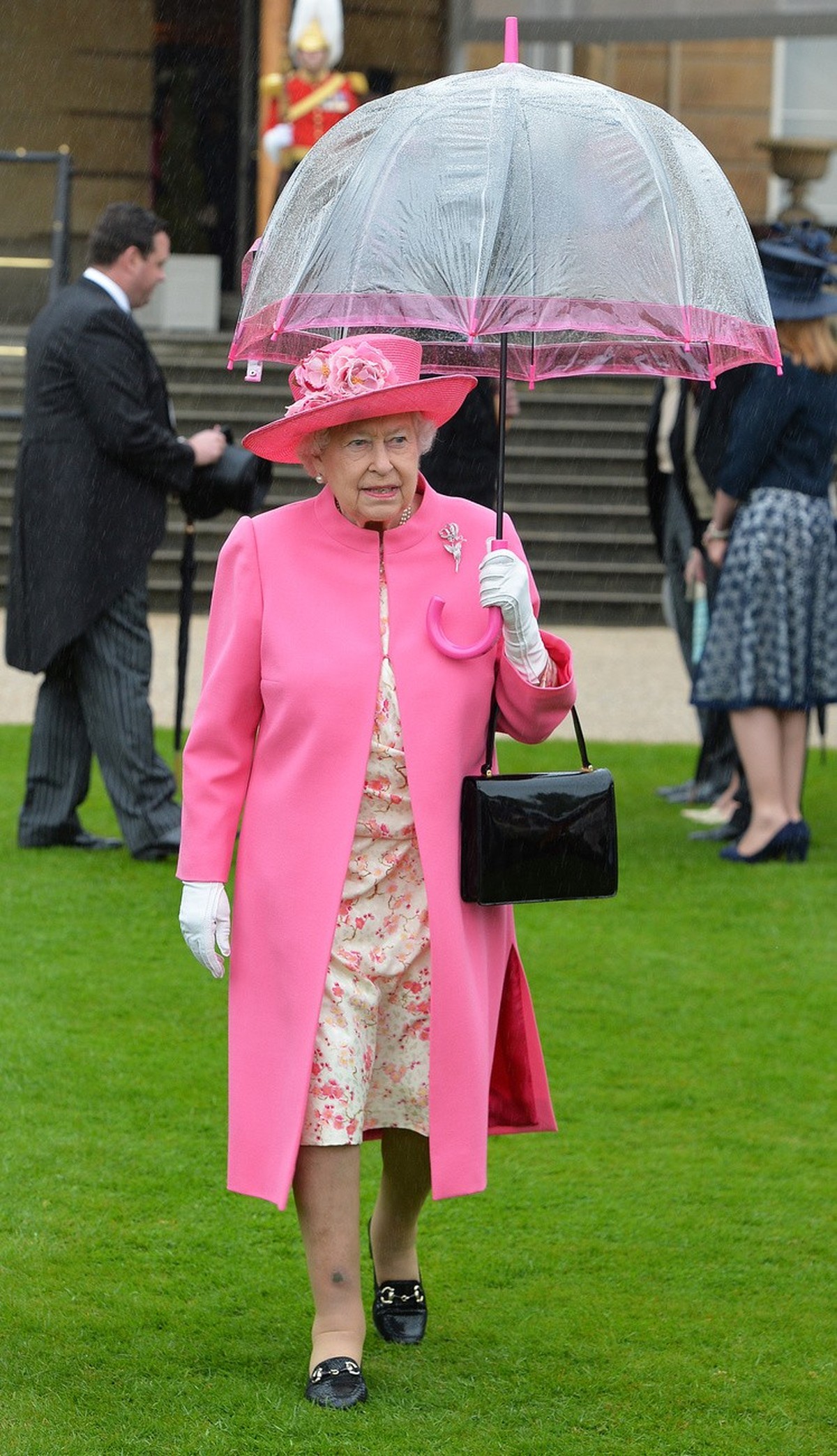 Britain's Queen Elizabeth II shelters from the rain under an umbrella at a garden party at Buckingham Palace in London, Tuesday May 10, 2016. Every summer, the Queen hosts at least three such par ...