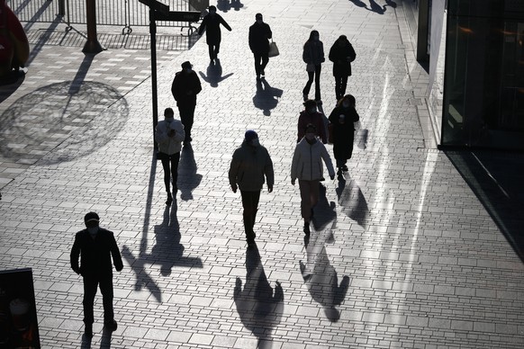 Visitors to a shopping mall cast shadows as they walk through a health check point in Beijing, China, Tuesday, Dec. 14, 2021. Chinese state media said Monday, Dec. 13, 2021, that the first case of the ...