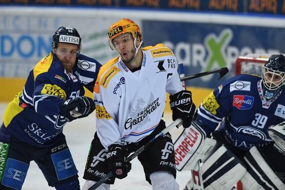 Ambri&#039;s player Jesse Zgraggen, left, fights for the puck with Fribourg&#039;s Top Scorer Julian Sprunger center, during the preliminary round game of National League A (NLA) Swiss Championship 20 ...