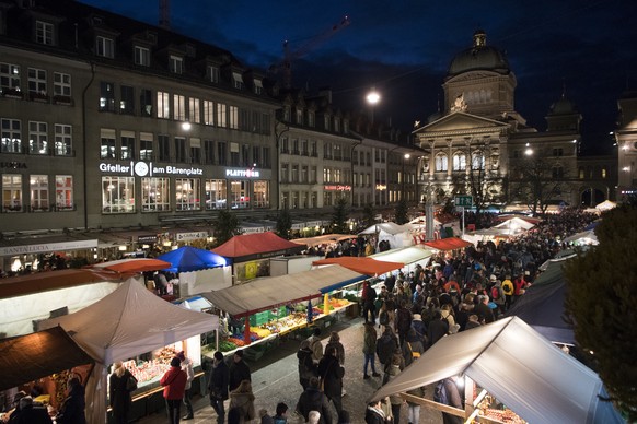 Besucher stroemen in den fruehen Morgenstunden durch die Strassen von Bern, im Hintergrund das Bundeshaus, waehrend dem traditionellen &quot;Zibelemaerit&quot;, am Montag, 27. November 2017, in Bern.  ...