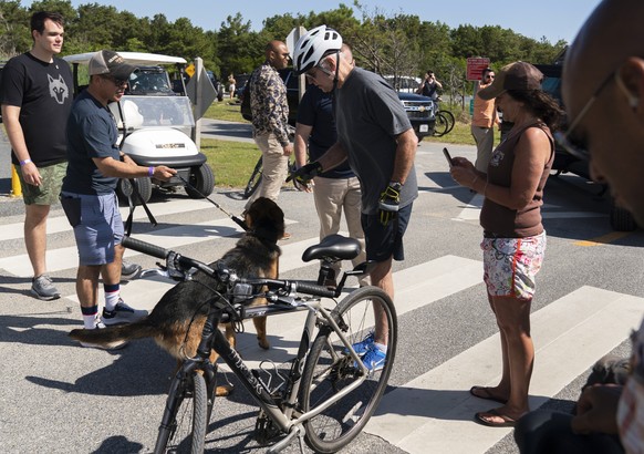 President Joe Biden communicates to his dog, Commander after greeting a crowd at Gordons Pond in Rehoboth Beach, Del., Saturday, June 18, 2022. Biden fell as he tried get off his bike to greet the cro ...