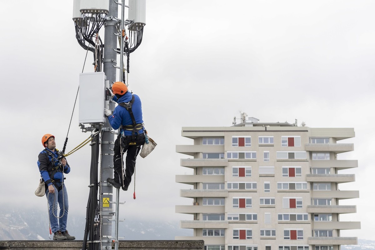 Deux employes de l'entreprise Axians installent une antenne 5G de communication pour les mobiles sur un mat situe sur le toit d'un immeuble du quartier de la Gradelle a Chene-Bougeries ce ve ...